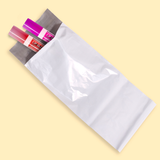 Bolsa blanca para envíos con artículos de papelería asomándose por la abertura.