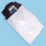 Bolsa blanca para envíos con un suéter oscuro doblado en el interior.
