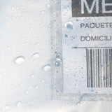 Detalle de gotas de agua sobre un sobre transparente con etiqueta de envío.